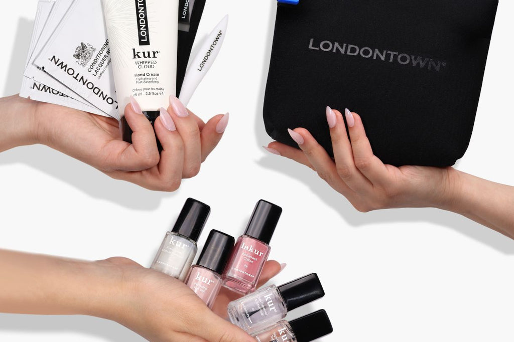 Hands holding Londontown nail care products and a black pouch against a white background.
